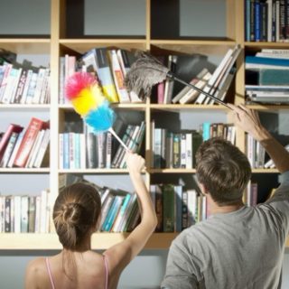 мужчина и женщина убирают пыль с полки
